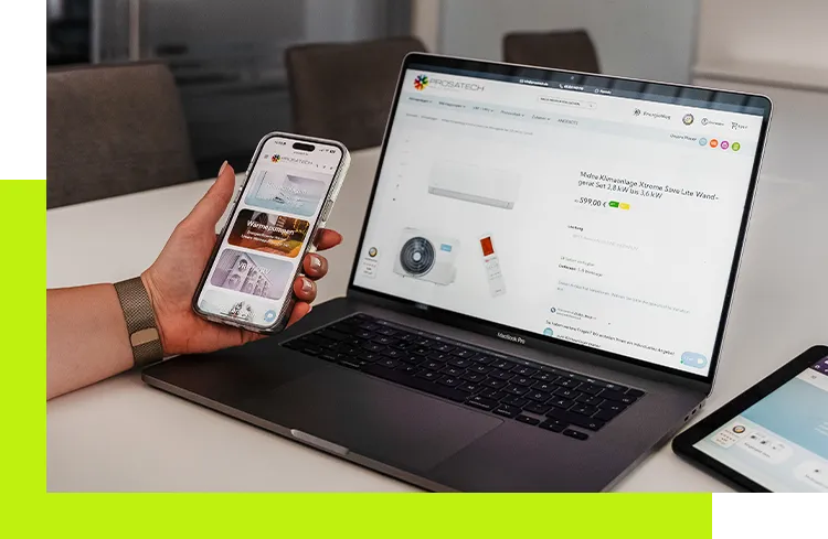 E-Commerce Plattformen - Hand hält ein Smartphone mit geöffneter Website neben einem Laptop, auf dem ebenfalls eine Produktseite angezeigt wird