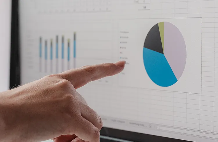 Social Media Advertising Agentur - Hand zeigt auf ein Kreisdiagramm am Monitor zur Analyse von Social-Media- oder Marketing-KPIs