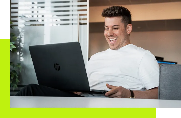 E-Mail Marketing Agentur - Geschäftsführer arbeitet am Laptop im Agenturbüro und lacht während des Austauschs über ein digitales Projekt