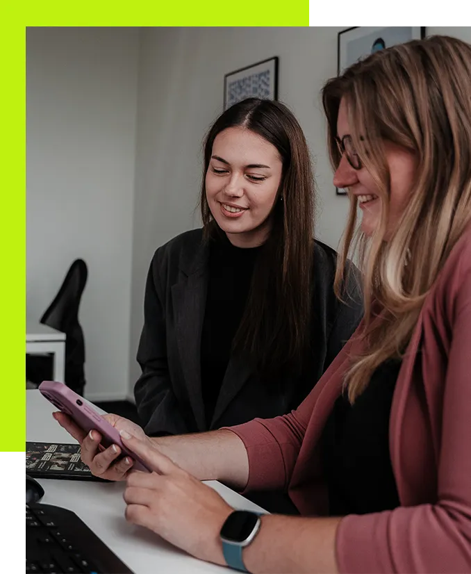 Social Media Management Agentur - Social Media Managerin zeigt Social-Media-Content auf einem Smartphone zur Abstimmung redaktioneller Inhalte